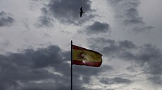 Lidé krá�ejí vedle �pan�lské vlajky s oblohou pokrytou mraky bou�e DANA. Po...