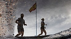 Lidé kráejí vedle panlské vlajky s oblohou pokrytou mraky boue DANA. Po...