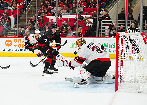 Branká� Ottawy Anton Forsberg zasahuje proti st�ele Martina Ne�ase z Caroliny.