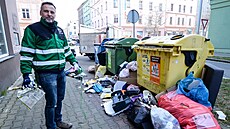 Pracovník �isté Plzn� douklízí nepo�ádek kolem popelnic.