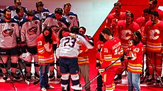 Sean Monahan z Columbusu a Mikael Backlund z Calgary objímají rodinu zesnulého...