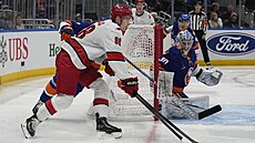 Útoník Caroliny Martin Neas vyváí puk zpoza branky New York Islanders.