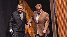 David Furnish pomáhá Eltonu Johnovi z pódia (�íjen 2024)