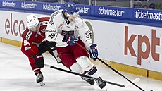 �eský hokejista Jakub Krej�ík si kryje puk p�ed Atilliem Biascou ze �výcarska.