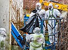 Technici v ochrannch oblecch demontuj azbestovou krytinu ped demolic dom,...
