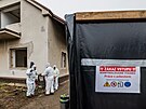 Technici v ochrannch oblecch demontuj azbestovou krytinu ped demolic dom,...