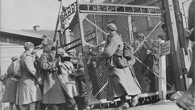 Sov�t�t� voj�ci otev�raj� br�ny koncentra�n�ho t�bora Osv�tim a osvobozuj� v�zn�. Nad br�nou je n�pis �Pr�ce osvobozuje�. (27. ledna 1945)