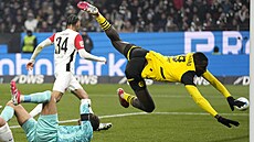 Serhou Guirassy z Dortmundu padá p�es branká�e Kevina Trappa z Frankfurtu.