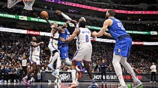 Kyrie Irving (uprosted v modrém) z Dallasu se tlaí do zakonení v utkání...