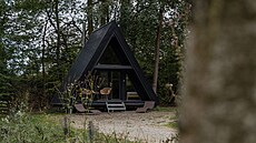 Chata se díky �erné barv� mezi stromy tém�� ztrácí.
