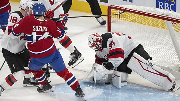 Jake Allen (34) v brn New Jersey lap puk  s pomoc Ondeje Palta (18). to Nick Suzuki (14) z Montrealu.