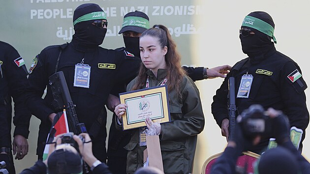 Izraelsk vojaka Agam Bergerov vedle maskovanch bojovnk Palestinskho islmskho dihdu, kdy je pedvna ervenmu ki v uprchlickm tboe Dablija v Gaze. (30. ledna 2025)