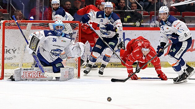 Hokejist Tince a Brna sleduj puk, kter poskakuje ped brankem Komety Michalem Postavou.