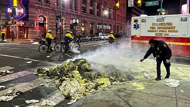 Policista kontroluje poz�statky po zap�len�ch v�cech b�hem oslav fanou�k� Philadelphia Eagles po v�h�e Super Bowlu.
