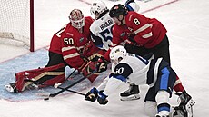 Cale Makar z Kanady se sna�í odklidit kotou� p�ed dotírajícím Joelem Armiou z...