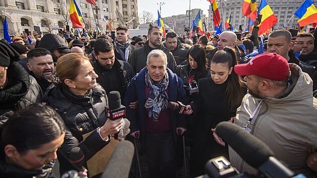 Prezidentsk� kandid�t Calin Georgescu po v�slechu na policii v obkl��en� p��znivc� a novin���. (26. �nora 2025)