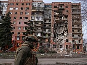 Ukrajinský voják prochází kolem obytné budovy pokozené ruskými vojenskými...