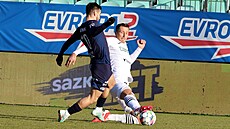 Stoper karvinských fotbalist� Dávid Kr�ík skluzem zasahuje mí� p�ed Michalem...