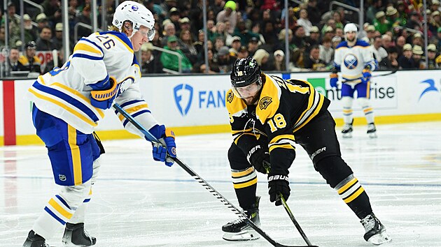 Rasmus Dahlin z Buffalo Sabres bojuje o puk s Pavlem Zachou z Boston Bruins.