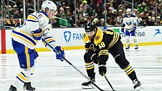 Rasmus Dahlin z Buffalo Sabres bojuje o puk s Pavlem Zachou z Boston Bruins.