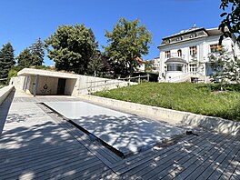 Snímek spodní �ásti zahrady se zakrytým bazénem a zast�e�enou pergolou t�sn� po...