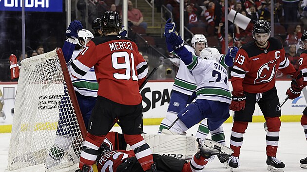 Skrum� p�ed brankou New Jersey, v pozad� se z g�lu raduje Pius Suter z Vancouveru.