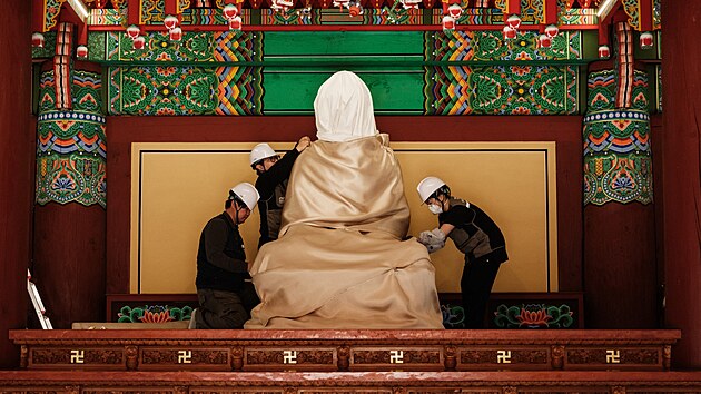 �lenov� Centra p��e o kulturn� d�dictv� Gyeongbuk Seobu v Ji�n� Korei po evakuaci v�ech ostatn�ch p�edm�t� zabalili sochu Buddhy do bavln�n� l�tky a neho�lav� deky. (25. b�ezna 2025)