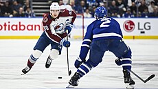 Martin Ne�as z Colorado Avalanche se blí�í k obránci Simonu benoitovi z Toronto...