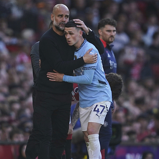 Phil Foden (vlevo) v objetí s Pepem Guardiolou poté, co byl vyst�ídání v derby...