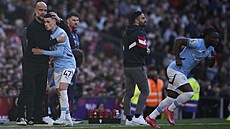 Phil Foden (vlevo) v objetí s Pepem Guardiolou poté, co byl vyst�ídání v derby...