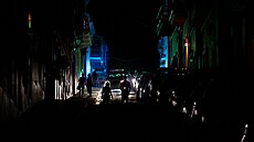 Svtla z policejního vozu osvtlují ulici, kterou procházejí lidé poté, co...