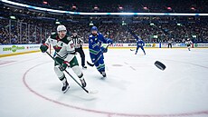 Marcus Foligno (vlevo) z Minnesoty a Filip Hronek z Vancouveru sledují letící...