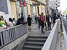 Lidé kontrolují své mobilní telefony a stojí p�ed uzav�enou stanicí metra po...