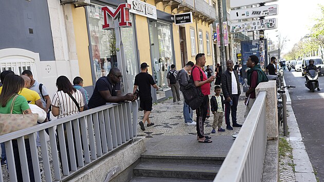 Lid� kontroluj� sv� mobiln� telefony a stoj� p�ed uzav�enou stanic� metra po v�padku proudu v portugalsk�m Lisabonu. (28. dubna 2025)