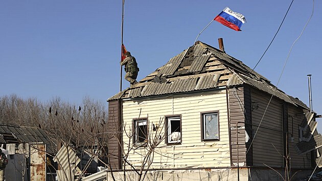 Rusk� voj�k vzty�uje vlajku nad domem v Kursk� oblasti. (14. b�ezna 2025)