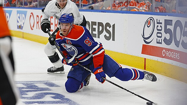 Connor McDavid na kolenou dr�� puk p�ed Adrianem Kempem.