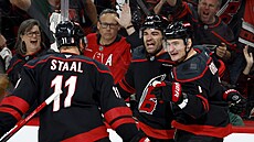 Jordan Martinook, Dmitrij Orlov a Jordan Staal slaví gól Carolina Hurricanes.