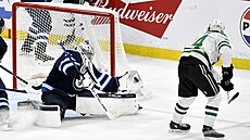 Connor Hellebuyck z Winnipeg Jets zasahuje v duelu s Dallas Stars proti pokusu...