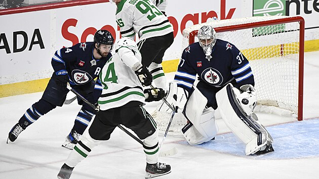G�lman Winnipegu Connor Hellebuyck sleduje puk p�ed svou brankou, natahuje se po n�m tak� Jamie Benn z Dallasu.