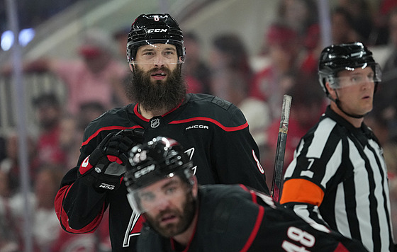 Brent Burns (nahoe) a Jordan Martinook z Carolina Hurricanes sledují hru.