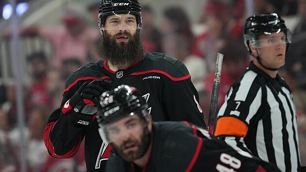 Brent Burns (naho�e) a Jordan Martinook z Carolina Hurricanes sledují hru.