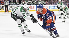 Connor McDavid (vpravo) z Edmonton Oilers útoí, tlaí na nj Cody Ceci z...