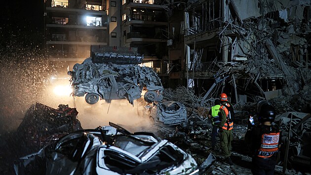 rn zatoil raketami na Izrael v odvet za tok idovskho sttu. Zchrani a bezpenostn pracovnci pracuj na mst dopadu rakety v izraelskm Ramat Ganu. (13. ervna 2025)