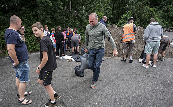 Lidé si v Tinci berou písek, který pro n pipravila tamní radnice ve...