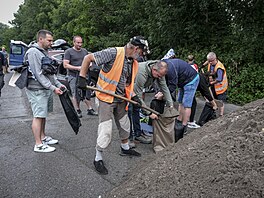 Lidé si v Tinci berou písek, který pro n pipravila tamní radnice ve...