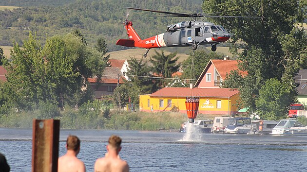 Na Litom��icku ho�� pole a les mezi obcemi Hrdly a Trav�ice nedaleko muni�n�ho skladu. V akci je vrtuln�k s bambivakem. Vodu nab�r� v Labi. (2. �ervence 2025)
