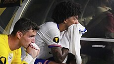 Zklamaní amerití fotbalisté Chris Richards a Matthew Freese sedí na lavice po...