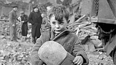 Oputný chlapec drí plyové zvíátko uprosted trosek po nmeckém leteckém...