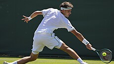 Jakub Meník se natahuje po balonku ve druhém kole Wimbledonu.