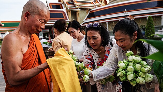 Thajci nabzej kvtiny buddhistickm mnichm bhem kvtinovho obadu v chrmu v thajskm Bangkoku. (11. ervence 2025)